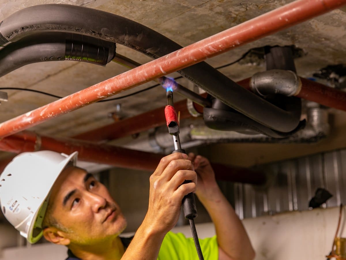 Skilful Star technician brazing pipework in a basement plant area