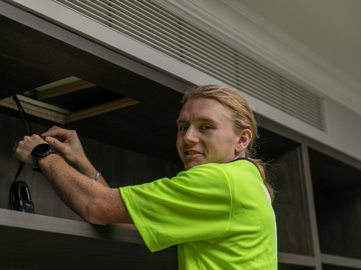 Skilful Star technician fitting a ducted air conditioning grille into joinery in a Sydney home
